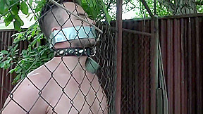 Caged bdsm sub gets cock tugged outdoors