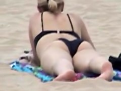 Candid beach babe is lying on the golden sand in bikini 03z