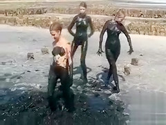 Young ladies coat their bodies in dark mud