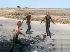 Young ladies coat their bodies in dark mud