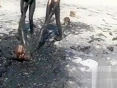 Young ladies coat their bodies in dark mud