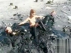 Young ladies coat their bodies in dark mud