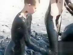 Young ladies coat their bodies in dark mud