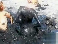 Young ladies coat their bodies in dark mud
