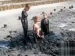Young ladies coat their bodies in dark mud