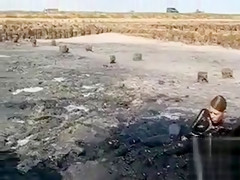 Young ladies coat their bodies in dark mud